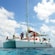 A group of people stand on a catamaran in the middle of the ocean